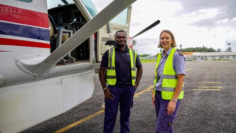 Two people stand by a small plane